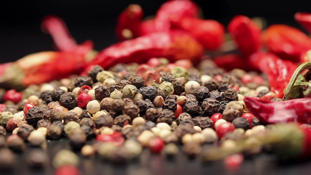 Pile of multi color peppercorns and dried chili, rotating