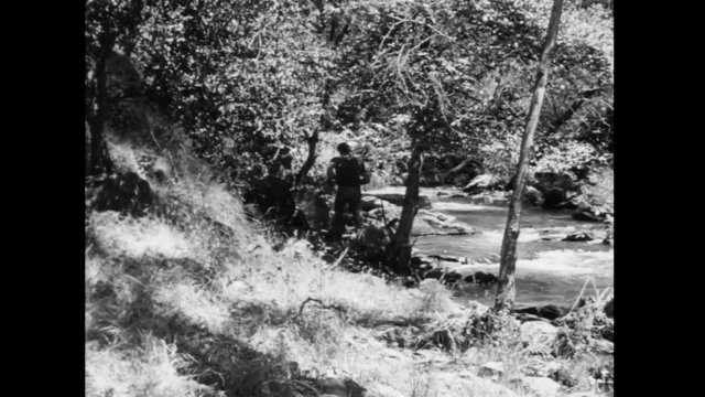 Rear view of man running along riverbank, 1940s