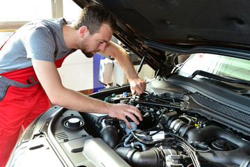 Fototapeta KFZ Mechaniker repariert Motor eines Fahrzeugs in der Autowerkstatt // Car mechanic repairs engine of a vehicle in the garage obraz