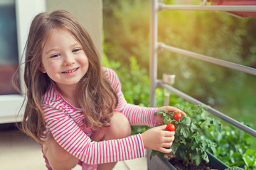 cute little girl holding growing tomatoes in pot