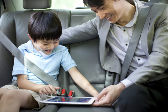 Happy father and son with digital tablet in car