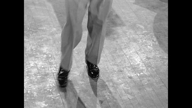 Low section of male tap dancer dancing on wooden floor, 1950s