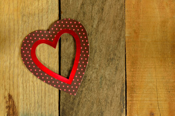 Valentines Day decorative heart set on pallet wood background, backdrop. Pink polka dots on brown with red strip interior shaped heart.