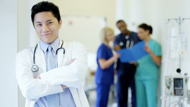 Portrait of confident Asian American male doctor in medical centre corridor