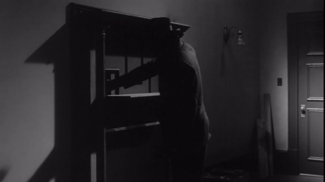 Burglar opens secret door in wall, 1950s