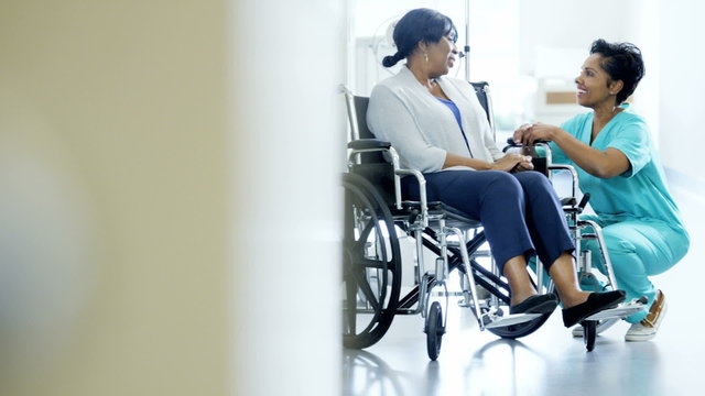 Portrait of African American female and patient on wheelchair in medical centre