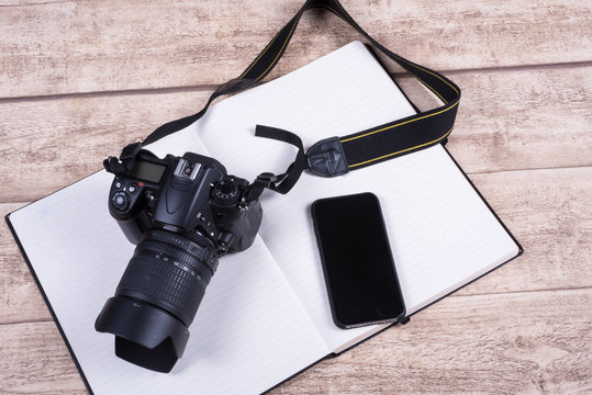 Fototapeta Photographers workplace with book, phone and camera on wooden ta