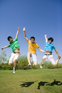 Three young men jumping in the air at the park