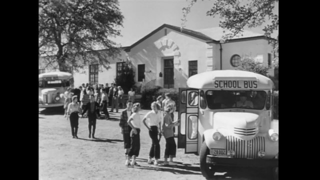 Wide shot of students boarding school bus, 1940s