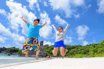 Father and daughter jumping with happy on beach near the sea under blue sky and cloud of summer at Koh Similan Island in Mu Ko Similan National Park, Phang Nga province, Thailand