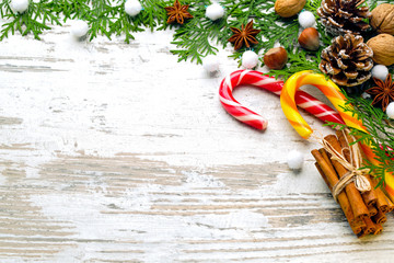 Traditional,Christmas,striped caramels,linking of sticks of spice of cinnamon,walnuts,pine cones,anisetree asterisks,fir-tree branches,artificial snow,on a light wooden background,place for the text 