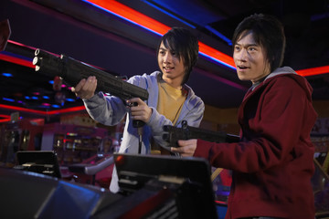 Obraz na płótnie Canvas Teenage Boys Playing Shooting Games At Arcade