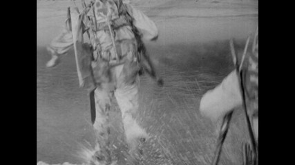 Soldiers jumping off boat and running towards shore
