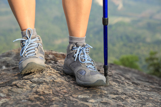 young woman hiker legs on mountain peak cliff