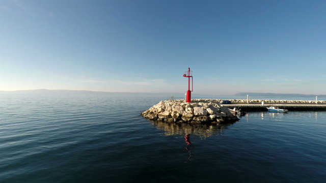 Passing by port entrance with red beacon light and calm blue sea