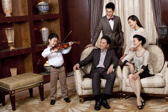 Little Boy Playing Violin In Front Of Family Members