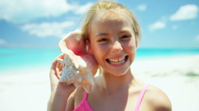 Portrait of a blonde female girl on a beach with a conch shell