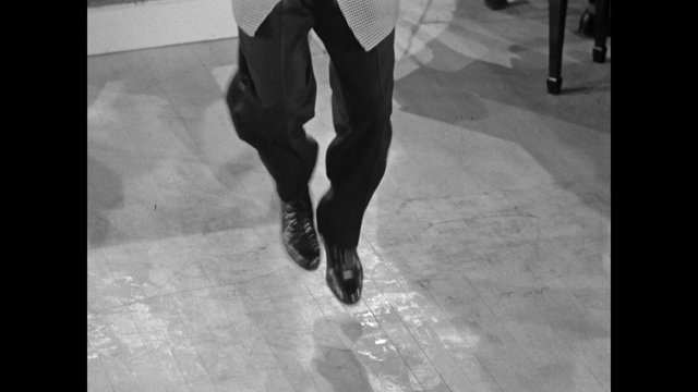 High angle view of performer tap dancing on wooden floor, 1950s