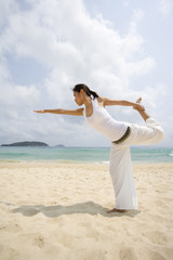 Young woman doing yoga on the beach