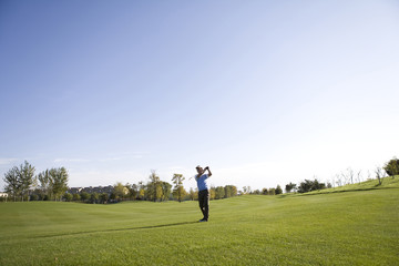 Man swinging golf club on golf course