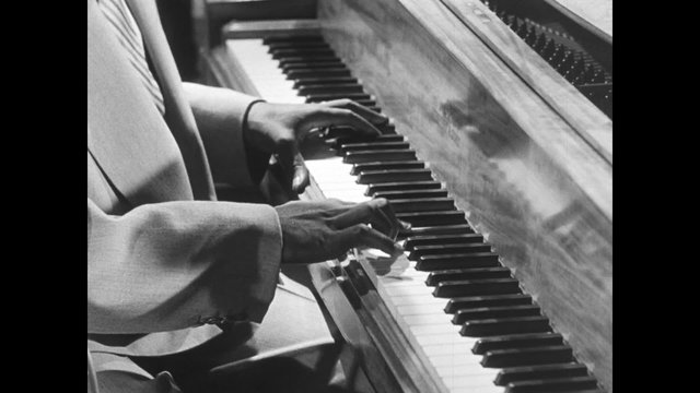 Medium shot of  lively jazz pianist playing piano, 1950s