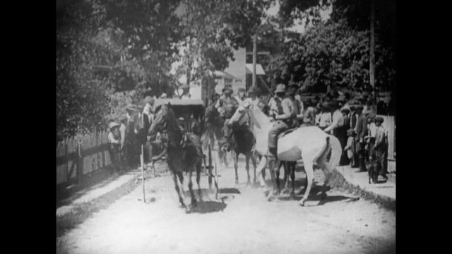 Men on horses accompanying horse cart  down street, 1920s