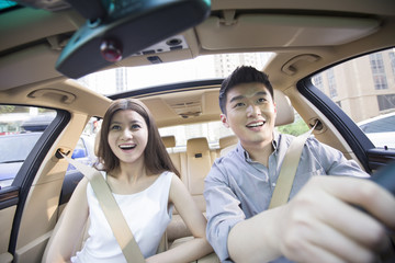 Naklejka premium Happy young couple in a car