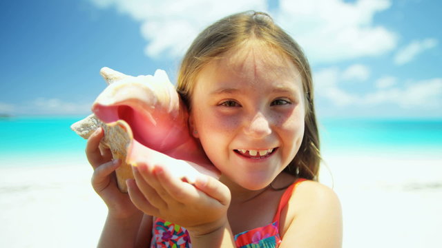 Portrait of a little Caucasian girl on a vacation beach with a conch shell