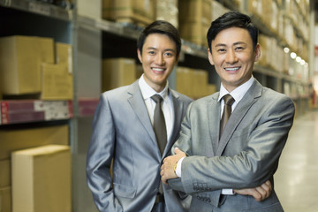 Confident business partners arms crossed in logistic warehouse