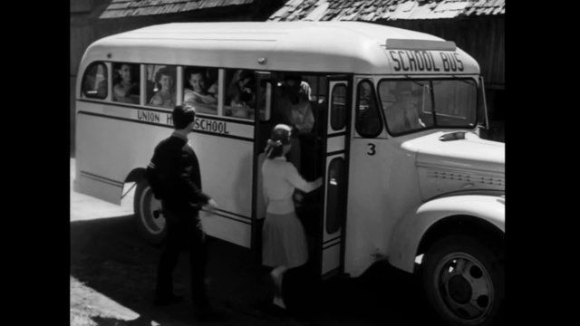 High school students boarding school bus on country road, 1940s