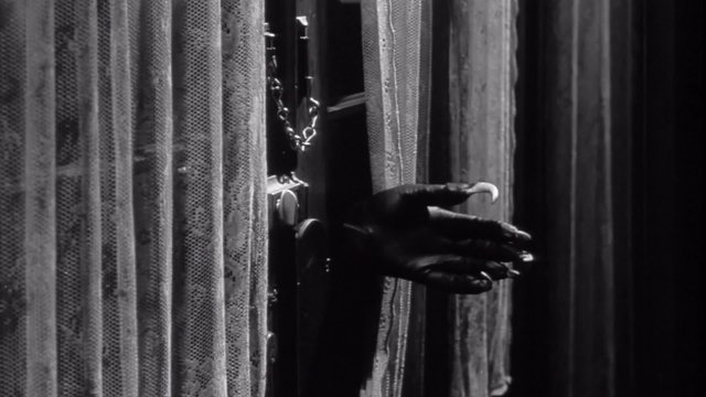 Man wearing claw glove making hole in glass and opening door