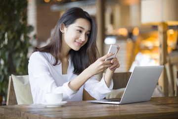 Fototapeta premium Young woman using smart phone in cafe