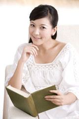 Naklejka premium Asian woman reading on a sofa