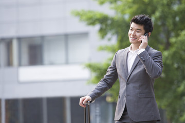 Young businessman talking on the phone with suitcase