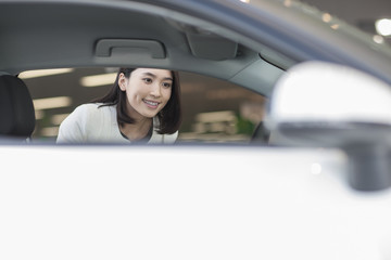 Young woman choosing car in showroom