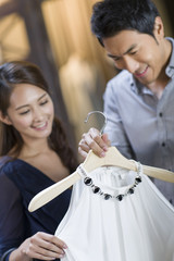 Young couple choosing dress in clothing store