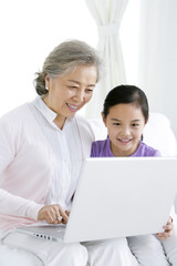 Chinese grandmother with grandaughter using a laptop