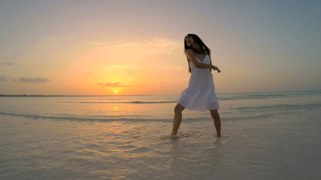 Young Asian Chinese girl in white dancing on ocean beach