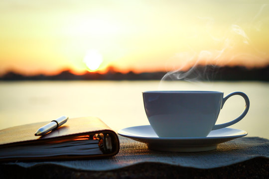 Fototapeta Silhouettes of sunrise morning coffee with a note and a pen