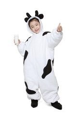 Cute girl in a cow costume with a glass of milk giving the thumbs-up sign