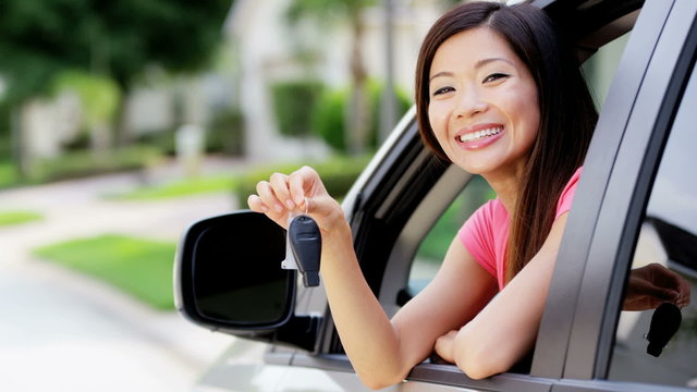 Portrait of young attractive Asian American female in rental car on holiday