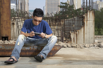 Man Playing Portable Video Game In Construction Site