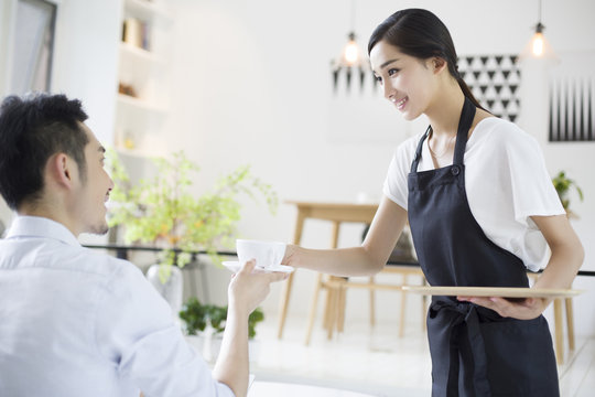 Waitress serving young man a cup of coffee