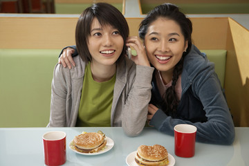 Teenage Girls Eating Burgers And Talking On Phone
