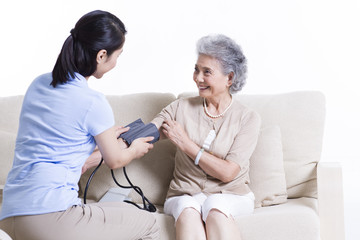 Nursing assistant taking senior woman's blood pressure