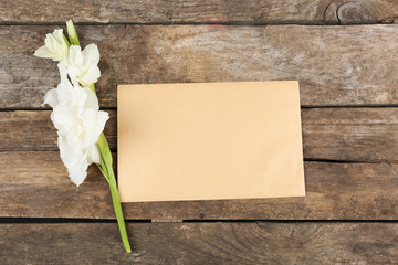 Blank card with beautiful gladiolus on wooden background