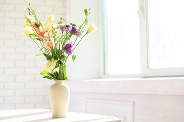 Beautiful spring flowers in vase on window background