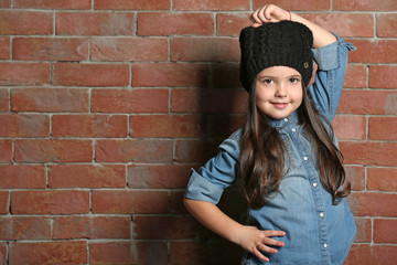 Portrait of little fashion kid girl on bricks wall background