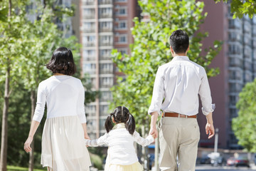 Young parents with daughter strolling hand in hand