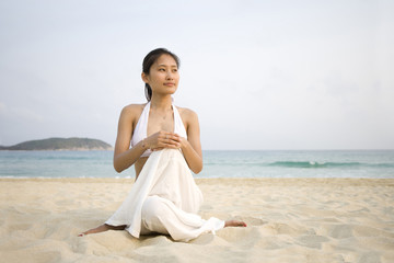 Fototapeta na wymiar Young woman doing yoga on the beach